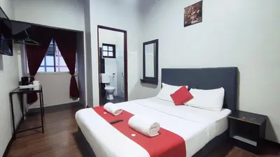 a bedroom with a large white bed with red pillows at Hotel Rasa Sayang 2 in Tanah Rata