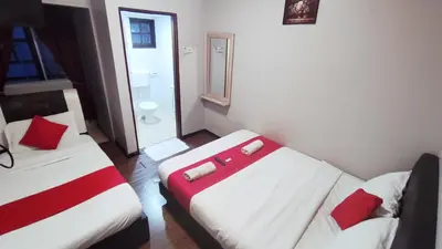 a hotel room with two beds and a suitcase at Hotel Rasa Sayang 2 in Tanah Rata