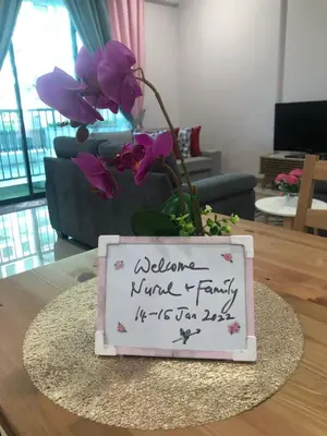 a sign on a table with a vase with purple flowers at Meru Oasis at Casa Kayangan Ipoh in Ipoh