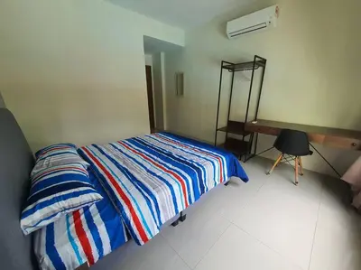 a bedroom with a bed with a striped blanket and a desk at Manhattan Condo Ipoh with Water Park and Pool View in Ipoh