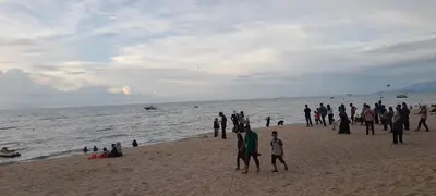 a group of people standing on a beach at AGODA C VIEW @ Sri Sayang Beach Resort in Batu Ferringhi