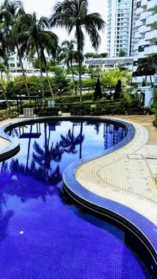 a large blue swimming pool with palm trees and buildings at AGODA C VIEW @ Sri Sayang Beach Resort in Batu Ferringhi