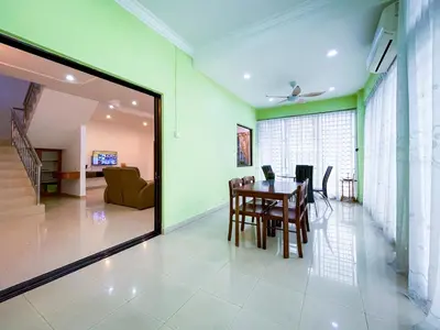 a dining room with a table and a living room at Tupai Mas Semi-D 4BR 2mins to LakeGarden & Zoo in Taiping