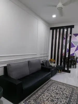 a living room with a black couch and a rug at Pelangi homestay in Kampung Bota Kiri