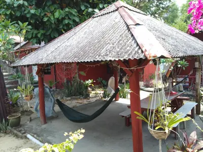 a hammock in a garden with a thatch roof at Nazri Nipah Camp Pangkor in Kampung Teluk Nipah