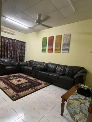 a living room with a black leather couch at HomestayMuslim Di Teluk Intan in Teluk Intan