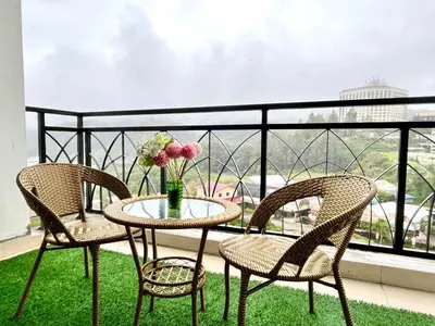 two chairs and a table with a vase of flowers on a balcony at Nova Sunrise n Mountain view Hilltop Hotel apartment in Nova Cameron Highlands in Brinchang