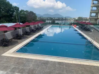 a large swimming pool with tables and red umbrellas at Marina Heights Hotel Residency in Lumut