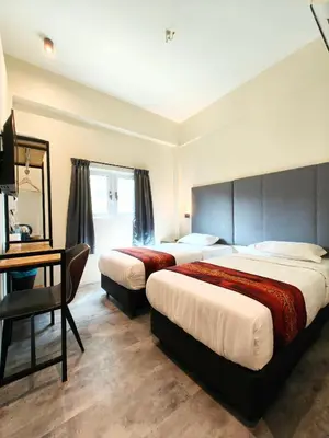 a hotel room with two beds and a desk at Pangkor Pop Ash Hotel in Pangkor