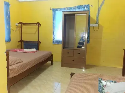 a bedroom with two beds and a dresser and a mirror at KAMILA MOTEL TELUK SENANGIN in Lumut