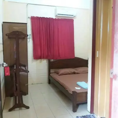 a small room with a bed with a red curtain at KAMILA MOTEL TELUK SENANGIN in Lumut