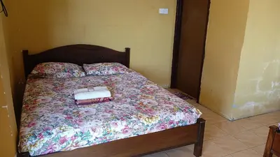 a bedroom with a bed with a floral bedspread at KAMILA MOTEL TELUK SENANGIN in Lumut