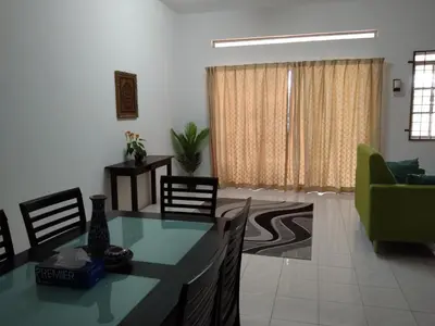 a living room with a dining table and a green couch at Afamily Homestay in Ipoh