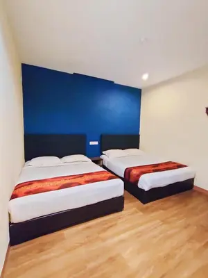 two beds in a room with a blue wall at HOTEL YTS in Brinchang