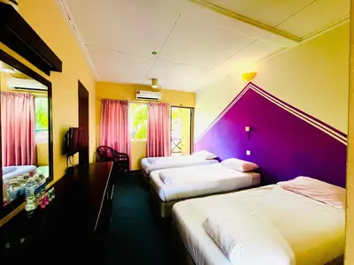 a hotel room with three beds and a purple wall at Kejora Garden Resort Pulau Pangkor in Pasir Bogak