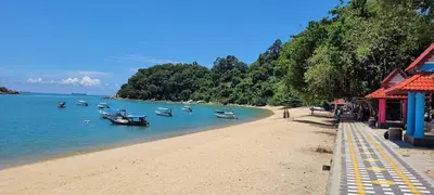 a beach with boats in the water and trees at Kejora Garden Resort Pulau Pangkor in Pasir Bogak