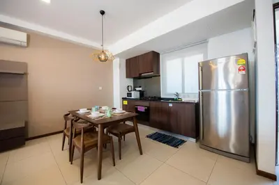 a kitchen with a table and a stainless steel refrigerator at The Landmark Penang in Tanjong Tokong