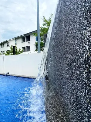 a pool of water next to a retaining wall at 18PAX 4BR Villa with Kids Swimming Pool, KTV, BBQ near SPICE Arena Penang in Bayan Lepas