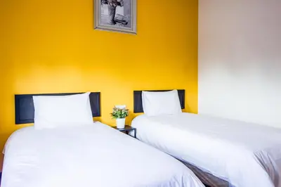 two beds in a room with a yellow wall at Explore 4BR Gardenhouse Retreats (Free Parking) in Butterworth