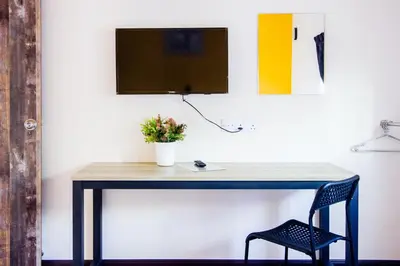 a desk with a chair and a monitor on a wall at Explore 4BR Gardenhouse Retreats (Free Parking) in Butterworth