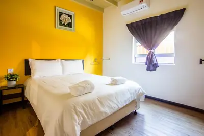a bedroom with a large bed with a yellow wall at Explore 4BR Gardenhouse Retreats (Free Parking) in Butterworth