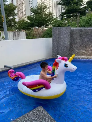 a young boy riding on an inflatable unicorn in a pool at 30PAX 7BR Villa with Kids Swimming pool, KTV, Pool Table n BBQ near SPICE Arena Penang 9800 SQFT in Bayan Lepas