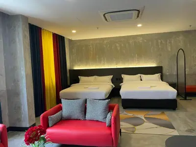a hotel room with two beds and a red chair at Sri Indar Hotel & Suites in Parit Buntar