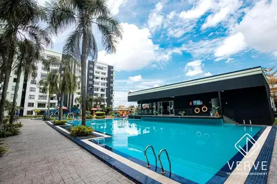 a swimming pool with palm trees in front of a building at Ipoh Manhattan Premium Suites by Verve in Ipoh