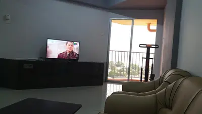 a living room with a flat screen tv and chairs at Coastside Homestay in George Town
