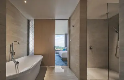 a bathroom with a bath tub and a bedroom at Amari SPICE Penang in Bayan Lepas