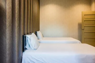 two beds in a hotel room with white sheets and pillows at Value Inn Homestay in Butterworth