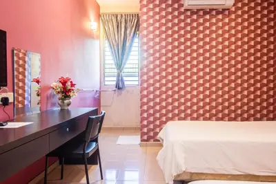a hotel room with a bed and a desk with flowers on it at Value Inn Homestay in Butterworth