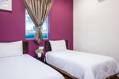 two beds in a room with a purple wall at Surprised Homestay Butterworth in Butterworth