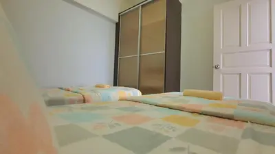 two beds in a room with a door and a bedroom at Kinta River Front Suites Ipoh by Beestay in Ipoh