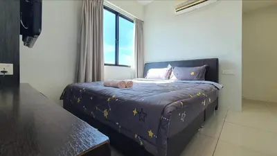a bedroom with a bed with a purple comforter and a window at Kinta River Front Suites Ipoh by Beestay in Ipoh