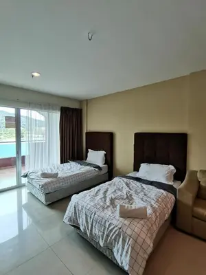 a bedroom with two beds and a chair in it at Spacious & Homey Apartment at Marina Island by JoMy Homestay in Lumut