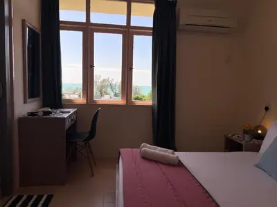 a bedroom with a bed and a window and a desk at EE's Summer House - Homestay 3 min walk to beach in Batu Ferringhi