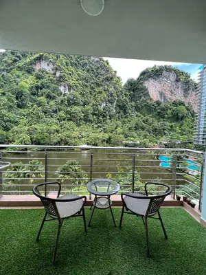 three chairs and a glass table on a balcony with mountains at Ipoh The Heyven Lakeside Homestay by Quadvanos in Ipoh