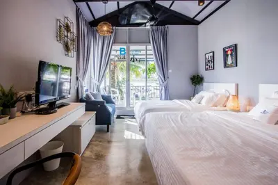a bedroom with two beds and a desk with a tv at Beachboy Chalet By The Beach in Bukit Lada
