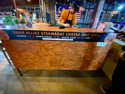 a man is standing at a food stand at BC Homestay @ Emerald Avenue Apartment, Brinchang in Brinchang