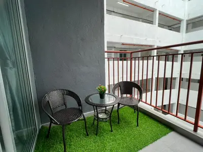 three chairs and a table on a balcony with grass at BC Homestay @ Emerald Avenue Apartment, Brinchang in Brinchang