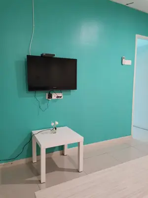 a room with a table and a tv on a blue wall at Peaceful 1-bedroom unit at Marina Island by JoMy Homestay in Lumut