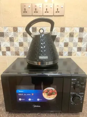 a tea kettle sitting on top of a microwave at Queen Room Semi Attached Bathroom Bukit Mertajam Alma Impian in Bukit Mertajam