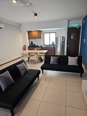 a living room with two black couches and a kitchen at Deluxe Seaview Suite Twin Bed by The Only Bnb in Tanjong Tokong