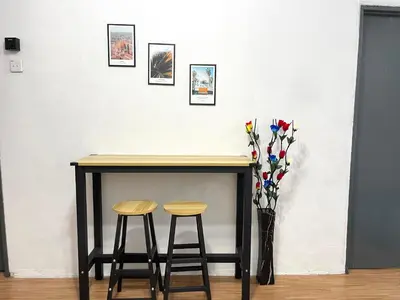 a table with two stools and a vase with flowers at Cozy 18 Entire 3 Bedroom @Alma Bukit Mertajam in Bukit Mertajam