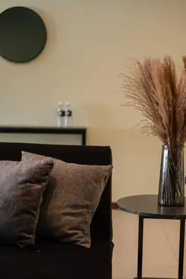 a couch with a pillow and a table with a vase of feathers at Deluxe Seaview Suite Twin Bed by The Only Bnb in Tanjong Tokong