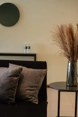a couch with a pillow and a table with a vase with feathers at Deluxe Seaview Suite Twin Bed by The Only Bnb in Tanjong Tokong