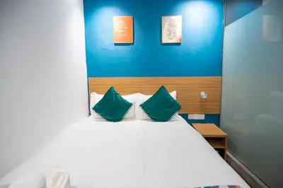 a bedroom with a white bed with two green pillows at Apollo Inn in George Town