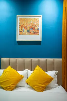 a bed with two yellow pillows and a blue wall at Apollo Inn in George Town