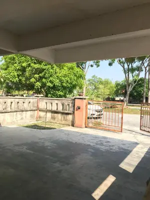 an empty parking lot with a gate and trees at Solehah Homestay in Seri Iskandar